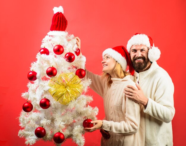 Frohe Feiertage, frohe Weihnachten und ein glückliches neues Jahr schönes Paar, das den Weihnachtsbaum romantisch schmückt