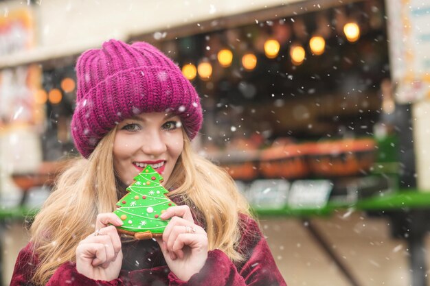 Frohe junge Frau, die leckeren Lebkuchen am zentralen Stadtplatz isst. Platz für Text