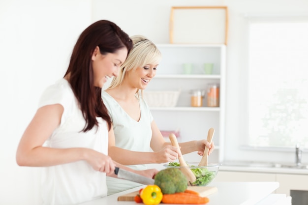 Frohe junge Frauen, die Abendessen vorbereiten