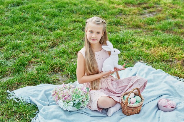 Frohe Osterhase. Kind, das Spaß im Freien hat. Kind, das mit Eiern und Kaninchen auf grünem Gras spielt.