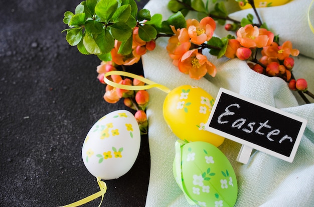 Frohe Ostern. dekorative Eier, blühender Frühlingszweig und Inschrift Ostern.