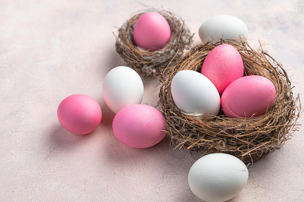 Frohe Ostern ein Nest mit weißen und rosa Ostereiern auf einem zarten Pastellhintergrund Seitenansicht