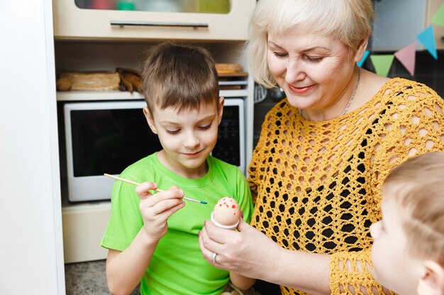 Frohe Ostern. Eine Großmutter und ihr Enkel malen Ostereier. Glückliche Familie, die Ostern zu Hause vorbereitet