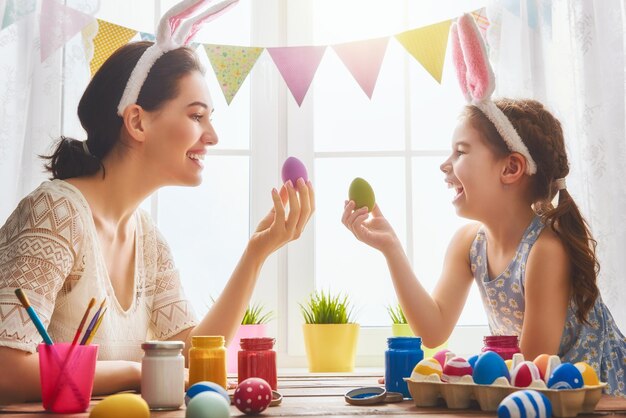 Frohe Ostern! Eine Mutter und ihre Tochter bemalen Ostereier. Glückliche Familie, die sich auf Ostern vorbereitet.