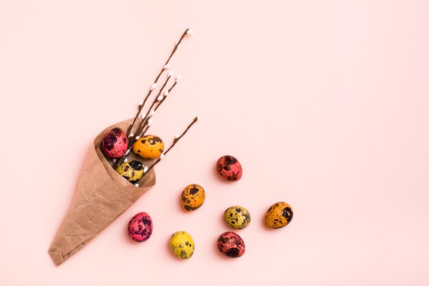 Frohe Ostern. Gemalte Wachteleier und Weidenkätzchen im Geschenkpapier auf rosa Hintergrund