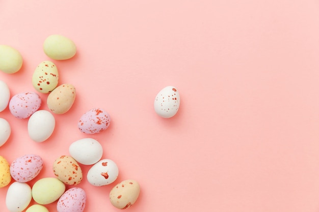 Frohe Ostern Konzept. Vorbereitung auf den Urlaub. Schokoladeneier der Ostersüßigkeit und Geleebonbons lokalisiert auf trendigem pastellrosa Hintergrund. Einfacher Minimalismus Flat Lay Draufsicht Kopierraum.