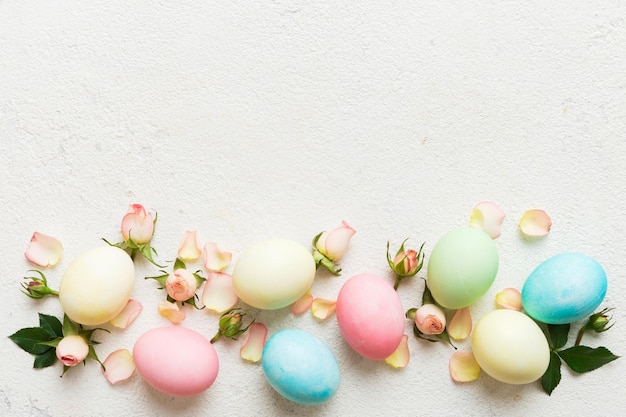 Frohe Ostern Ostereier auf farbigen Tischen mit gelben Rosen Natürliche gefärbte farbige Eier Hintergrund Top-View mit Kopierraum