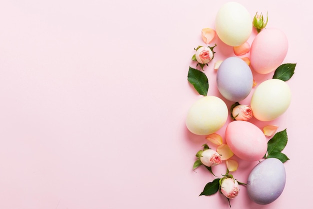 Frohe Ostern Ostereier auf farbigen Tischen mit gelben Rosen Natürliche gefärbte farbige Eier Hintergrund Top-View mit Kopierraum