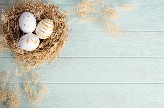 Frohe Ostern, Ostern gemalte Eier im Nest auf rustikalem Holztisch für Ihre Dekoration im Urlaub. Draufsicht mit Kopierraum.