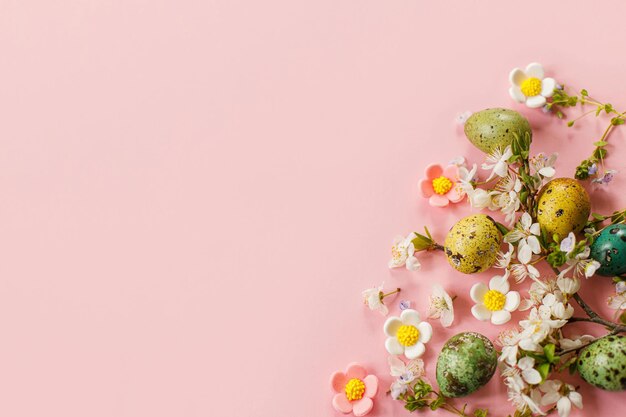 Frohe Ostern Ostern stilvolle Eier und blühende Frühlingsblumen auf rosa Hintergrund Platz für Text Moderne Grußkarte oder Banner Natürlich bemalte bunte Wachteleier und Kirschblüte