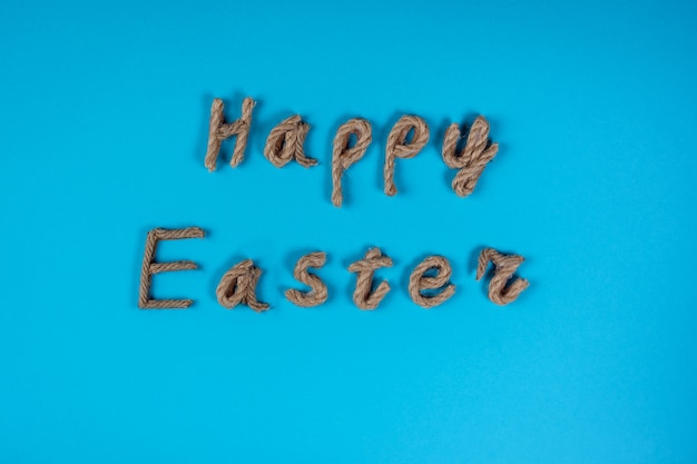 Frohe Ostern Schriftzug gemacht von Seil auf dem blauen Hintergrund. Ostern, Gruß oder Einladungskarte feiern. Sprigtime.