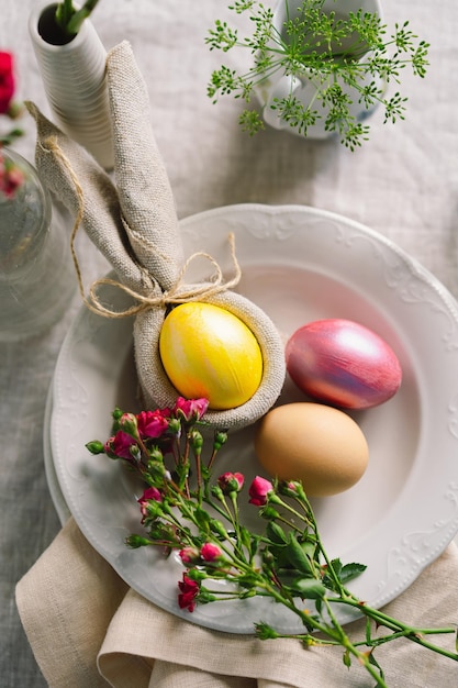 Frohe Ostern Stilvolle Ostereier auf einer Serviette mit Frühlingsblumen auf weißem Holzhintergrund Tabelleneinstellung Das Konzept eines fröhlichen Osterurlaubs