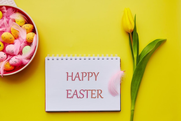 Frohe Ostern wünschen Rosa Schale mit bunten Eiern und rosa Federn Postkarte auf leuchtend gelbem Hintergrund