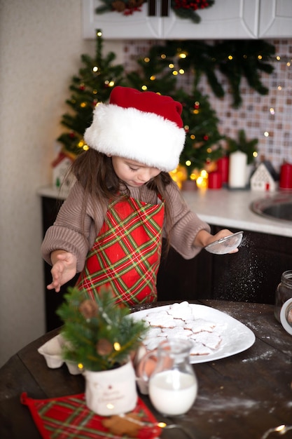Frohe Weihnachten Ein lustiges süßes Mädchen in einer gemütlich eingerichteten Küche hat Weihnachtsplätzchen gebacken und isst sie Lifestyle Warme Töne