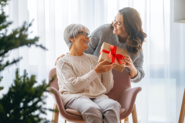 Frohe Weihnachten Frohe Feiertage Ältere Mutter und ihre erwachsene Tochter beim Austausch von Geschenken