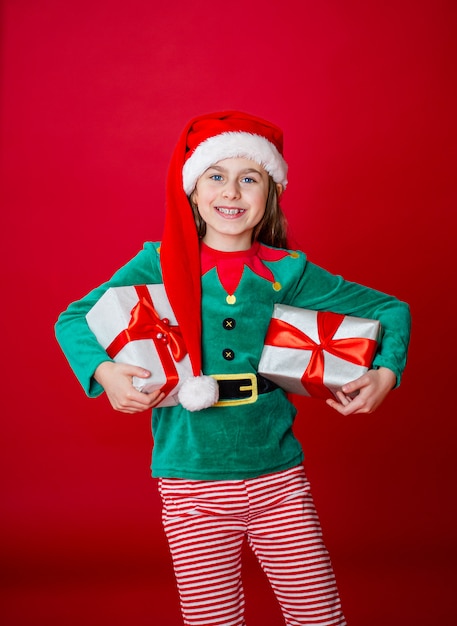 Frohe Weihnachten, glückliches attraktives Mädchen mit Geschenken in einem Kostüm von Santa Claus-Helferelfen
