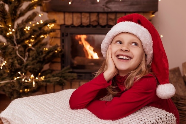 Frohe Weihnachten Kind wartet auf den Weihnachtsmann in weihnachtlicher Atmosphäre zu Hause mit Weihnachtsbaum, Kamin