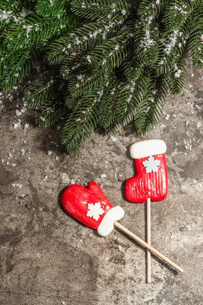 Frohe Weihnachten Kranz aus Tannenzweigen und Lutschern auf Steinbeton Hintergrund. Weihnachts- und Neujahrsferien, modernes hartes Licht, dunkler Schatten. Kunstschnee, flache Lage, Draufsicht