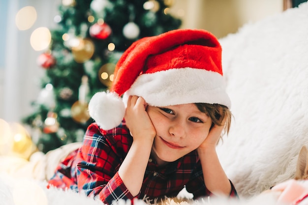 Frohe Weihnachten lustiges nachdenkliches kleines Kind auf der Couch liegend mit Decke in den Winterferien Kind Junge