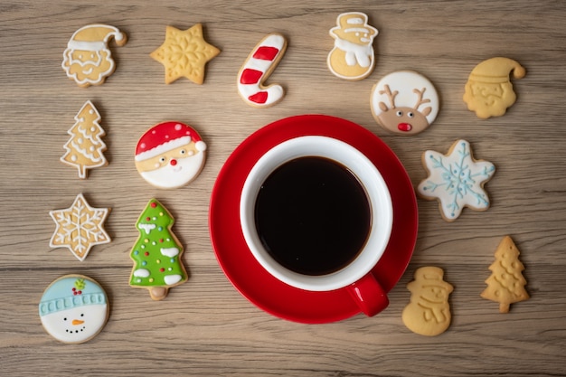 Frohe Weihnachten mit hausgemachten Keksen und Kaffeetasse auf Holztischhintergrund. Weihnachtsabend-, Party-, Feiertags- und Frohes neues Jahr-Konzept