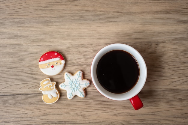 Frohe Weihnachten mit hausgemachten Keksen und Kaffeetasse auf Holztischhintergrund. Weihnachtsabend-, Party-, Feiertags- und Frohes neues Jahr-Konzept