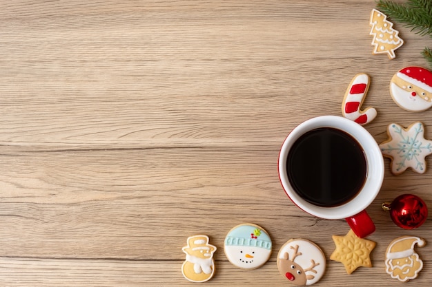 Frohe Weihnachten mit hausgemachten Keksen und Kaffeetasse auf Holztischhintergrund. Weihnachtsabend-, Party-, Feiertags- und Frohes neues Jahr-Konzept