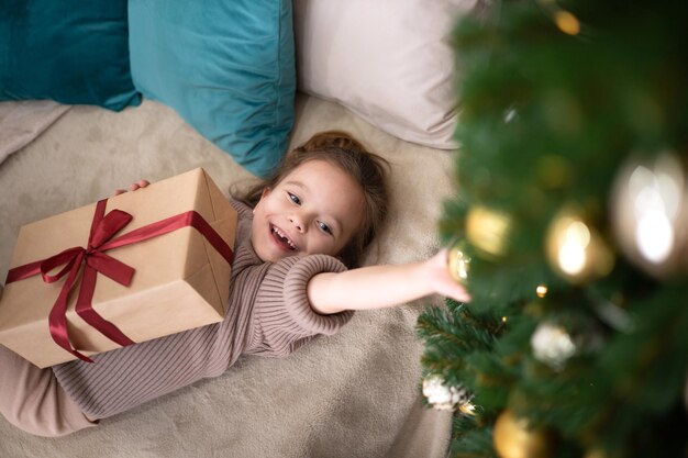 Frohe Weihnachten Porträt eines lustigen Mädchens mit einem gefallenen Milchzahn auf dem Hintergrund eines Weihnachtsbaums mit brennenden Lichtern Lifestyle Platz für Text