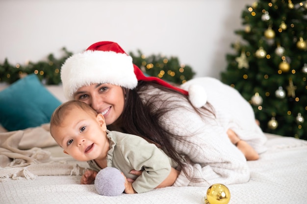 Frohe Weihnachten Schöne Mutter und kleine Tochter in einem für den Urlaub dekorierten Schlafzimmer Glücklicher Familienlebensstil