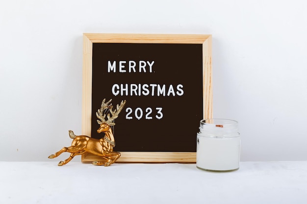 Frohe Weihnachten-Schriftzug auf Briefbrett Öko-Baum und goldener Hirsch minimalistischer Neujahrshintergrund 2023