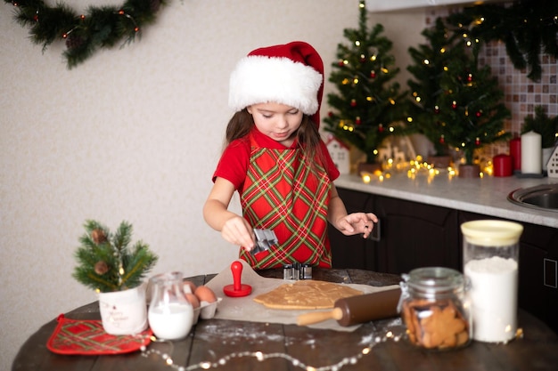 Frohe Weihnachten Süßes Mädchen macht Weihnachtsplätzchen in ihrer dekorierten Küche Lichter und einen Weihnachtsbaum Lifestyle Platz für Text