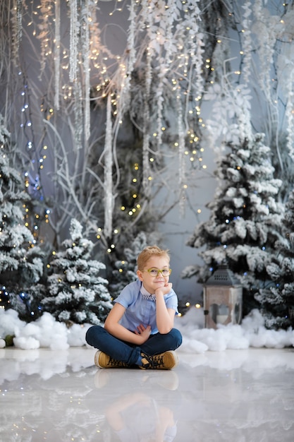 Frohe Weihnachten und ein glückliches Neues Jahr! Charmanter kleiner Junge sitzt zu Hause