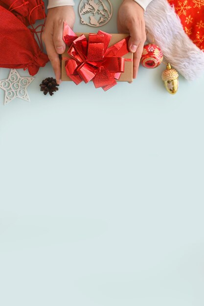 Foto frohe weihnachten und ein glückliches neues jahr. die hände eines mannes halten eine geschenkbox aus kraftpapier neben anderen überraschungen in tüten.