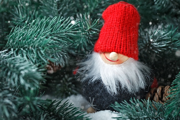 Frohe Weihnachten und ein glückliches Neues Jahr. Toy Santa in den Zweigen einer Fichte. Tiefenschärfe.