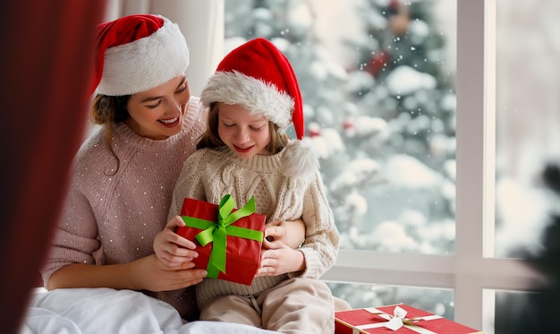 Frohe Weihnachten und frohe Feiertage fröhliche Mutter und ihre süße Tochter tauschen Geschenke aus