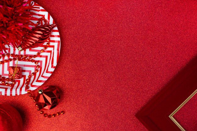 Frohe Weihnachten und Neujahr rot. Draufsicht des Lamettas, Geschenkbox, Ball, Band verzieren auf funkelnder Tabelle