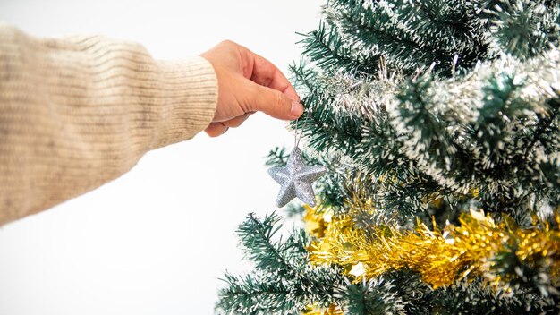 Frohe Weihnachten und schöne Feiertage, die Hand eines Mannes schmückt die Fichte im Winter zu Hause. Weihnachtssterne hängen von Tannenzweigen für Dekorationsbanner, Neujahrskonzept.