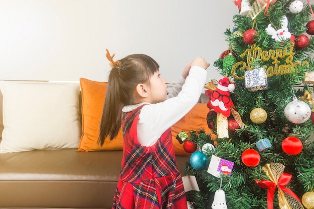 Frohe Weihnachten und schöne Feiertage! Feiertags- und Kindheitskonzept. Glückliches kleines lächelndes Mädchen mit Weihnachtsgeschenkbox.