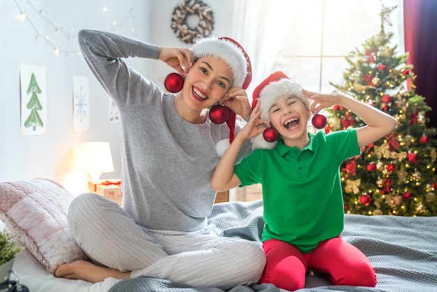 Frohe Weihnachten und schöne Feiertage! Mutter und Tochter haben Spaß im Bett. Der Morgen vor Weihnachten. Porträt liebevolle Familie.