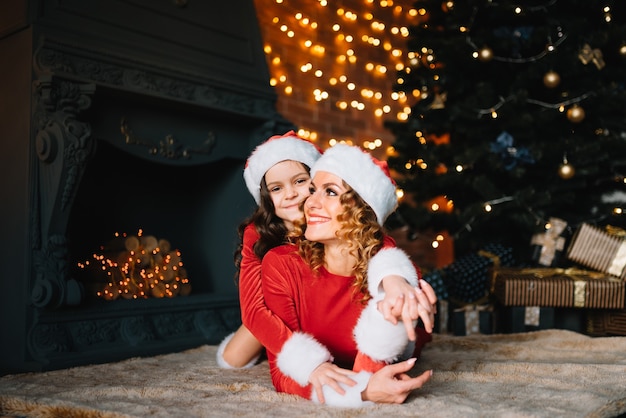 Frohe Weihnachten und schöne Feiertage! Schöne Mutter mit kleiner Tochter in Weihnachtskostümen verbringen Zeit zusammen in der Nähe des Weihnachtsbaums.