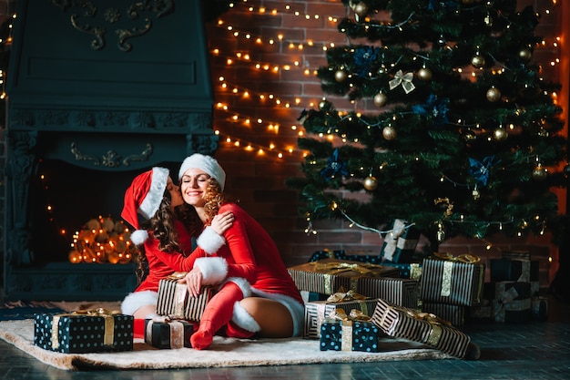 Frohe Weihnachten und schöne Feiertage! Schöne Mutter mit kleiner Tochter in Weihnachtskostümen verbringen Zeit zusammen in der Nähe des Weihnachtsbaums.