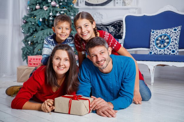 Frohe Weihnachten und schöne Feiertage. Schöne vierköpfige Familie, die Spaß im Weihnachtsinnenraum hat.