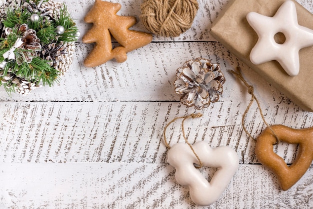 Frohe Weihnachtskonzepte mit Geschenkbox, Gebäck und Ornamentelement auf weißem Holztischhintergrund mit Kopierraum