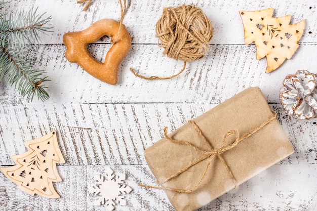 Frohe Weihnachtskonzepte mit Geschenkbox, Gebäck und Ornamentelement auf weißem Holztischhintergrund mit Kopierraum