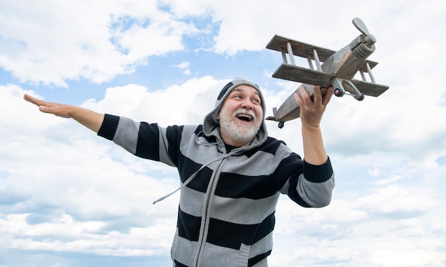 Froher älterer Mann im Ruhestand reifer Mann im Ruhestand alter Mann auf Himmelshintergrund mit Spielzeugflugzeug im Freien