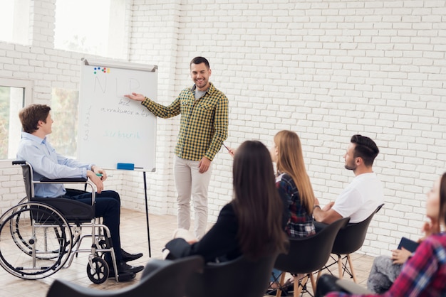 Froher junger Mann zeigt Hand auf das Flipchart, das NLP beschriftet wird.