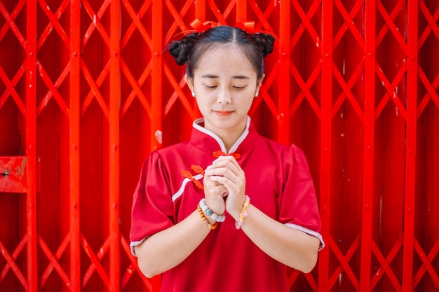 Frohes chinesisches neues Jahr. Asiatische Frau, die traditionelles Cheongsam-Qipao-Kleid mit Congra-Geste trägt