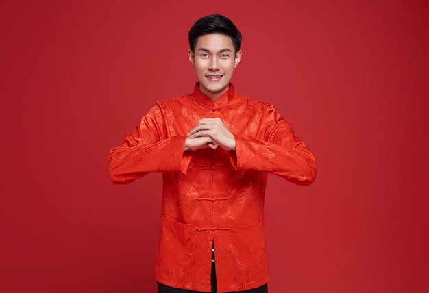 Frohes chinesisches Neujahr, asiatischer Mann in roter Kleidung mit Glückwunschgeste