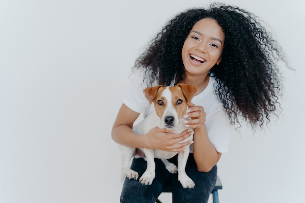 Frohes gelocktes Mädchen, das ihren Hund streichelt und sich freut, Jack-Russell-Terrier zu kaufen,