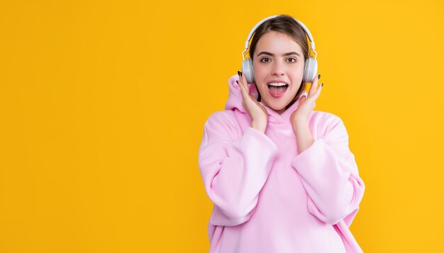 Frohes Mädchen hört Musik in Kopfhörern auf gelbem Hintergrund