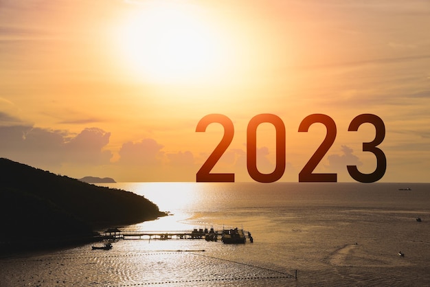 Frohes neues Jahr 2023 Meer Berg Sonnenuntergang Erfolgskonzept Silhouette der Insel Meer Bergblick Sonnenlicht Erfolg mit Sonnenuntergang Hintergrund Frohes neues Jahr 2023 Verwendung für Web-Banner und Werbung